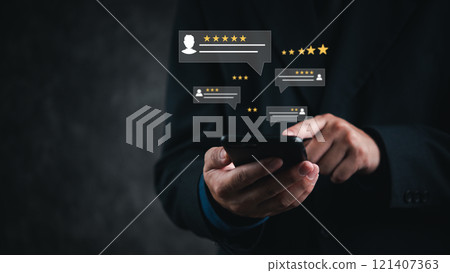 A hand holds a smartphone with floating review icons, symbolizing customer feedback on a digital platform. 121407363