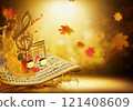 A golden treble clef sits on a sheet of music, musical notes on a flowing, dancing autumn leaves in golden Color 121408609