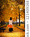A woman playing amongst fallen ginkgo leaves in an autumn park 121409168