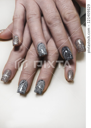Acrylic nail extensions with a snake design and glitter gel polish. Manicure Acrylic nail extensions with a snake design and glitter gel polish. Manicure 121409829