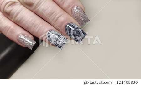 Acrylic nail extensions with a snake design and glitter gel polish. Manicure Acrylic nail extensions with a snake design and glitter gel polish. Manicure 121409830