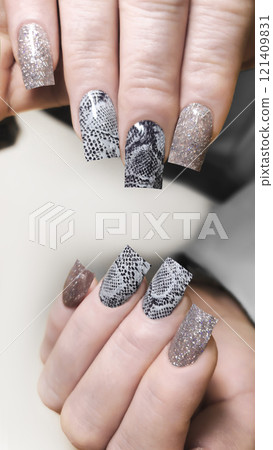Acrylic nail extensions with a snake design and glitter gel polish. Manicure 121409831