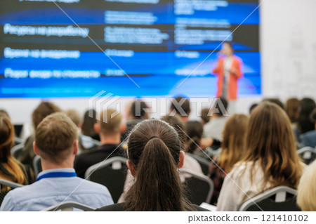 Audience at a business presentation focused on a speaker on a stage 121410102