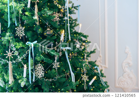 Christmas tree branches adorned with glass ornaments and ribbons on white plaster wall background Christmas tree branches adorned with glass ornaments and ribbons on white plaster wall background 121410565