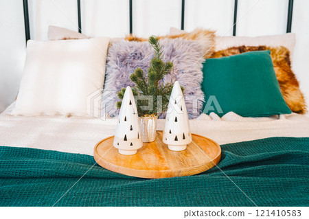 Cozy bedroom setup with festive Christmas decor and bed with green blanket and decorative pillows 121410583