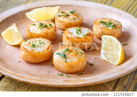Fried scallops with butter, lemon, parsley on rustic yellow wooden table 121410827