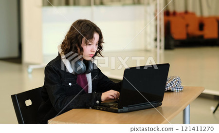 A child with headphones sits at a desk, intently using a laptop. The scene reflects the growing role of e-learning and digital tools in shaping the future of education and work-life balance. 121411270