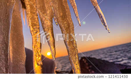 Icicle from sea wave close-up. Sunset. Sea in the background 121411430