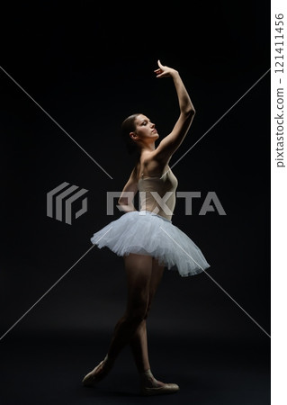 Ballet dancer performing in a graceful pose under dramatic lighting 121411456