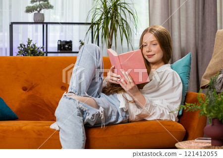 Teen girl relaxing interesting book turning pages smiling enjoying literature taking a rest on sofa Teen girl relaxing interesting book turning pages smiling enjoying literature taking a rest on sofa 121412055