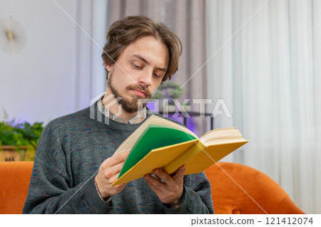 Bearded man reading interesting book turning pages smiling enjoying literature taking a rest at home Bearded man reading interesting book turning pages smiling enjoying literature taking a rest at home 121412074