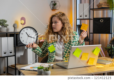 Tired businesswoman using laptop sticky notes with many tasks overworked checking time on clock Tired businesswoman using laptop sticky notes with many tasks overworked checking time on clock 121412123