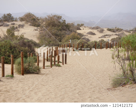 A walking trail fenced with wooden posts in a sand desert dune in Maspalomas, Gran Canaria A walking trail fenced with wooden posts in a sand desert dune in Maspalomas, Gran Canaria 121412172