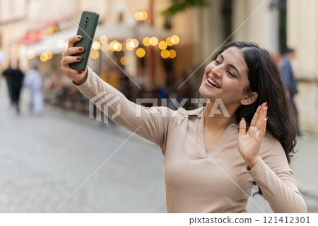 Indian woman blogger taking selfie on smartphone video call online with subscribers on city street Indian woman blogger taking selfie on smartphone video call online with subscribers on city street 121412301