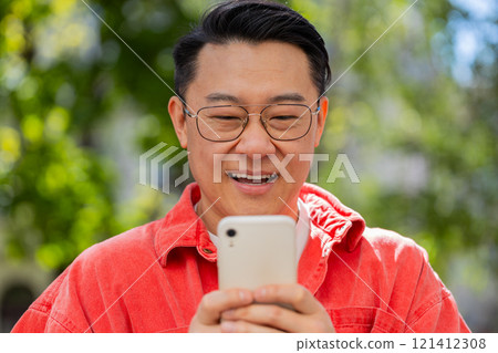 Asian middle-aged man using smartphone typing text messages in social media application online Asian middle-aged man using smartphone typing text messages in social media application online 121412308