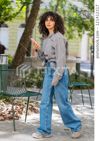 Tourist young curly hair woman using smartphone typing text messages looking for search a way on map 121412317
