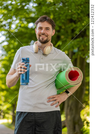 Athletic fitness sport runner man with yoga mat drinking water from bottle after training exercise Athletic fitness sport runner man with yoga mat drinking water from bottle after training exercise 121412332