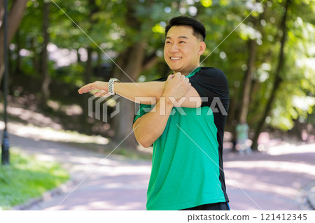 Japanese sporty healthy man athlete in park outdoors stretching hands stretch arms morning workout Japanese sporty healthy man athlete in park outdoors stretching hands stretch arms morning workout 121412345
