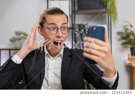 Happy amazed young Caucasian businessman working on smartphone shocked by sudden victory at home 121412361