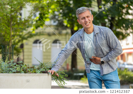 Caucasian man traveler feeling sudden strong abdominal stomach ache gastritis problem on city street 121412387
