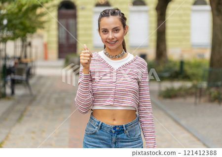 Woman showing thumbs up, like sign positive something good positive feedback in urban city street 121412388