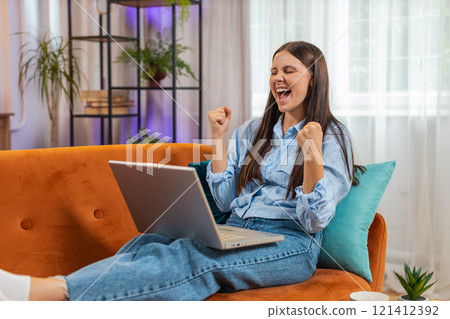 Surprised happy young woman using laptop computer, receive good news email message at home room 121412392