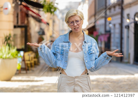 Doubtful sad frustrated young Caucasian woman shrugging shoulders dont know answer on city street Doubtful sad frustrated young Caucasian woman shrugging shoulders dont know answer on city street 121412397