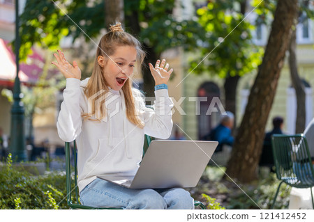 Happy woman freelancer working on laptop screams in triumph win celebrating success sitting on chair 121412452