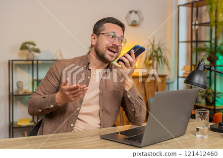 Caucasian young businessman working having mobile phone loudspeaker talk at home office desk 121412460