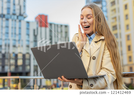 Overjoyed happy mature businesswoman working on laptop screaming in delight on downtown city street 121412469