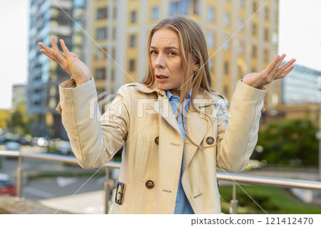 Doubtful sad frustrated mature Caucasian woman shrugging shoulders dont know answer on city street 121412470