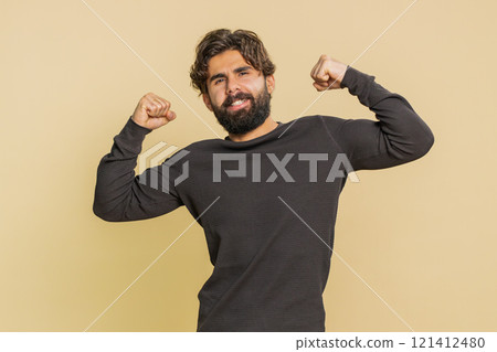 Fit sporty man showing biceps and looking confident, feeling power strength on beige background 121412480