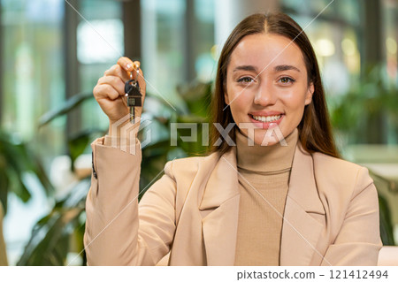 Caucasian young businesswoman real estate agent showing the keys of new home in office lobby 121412494
