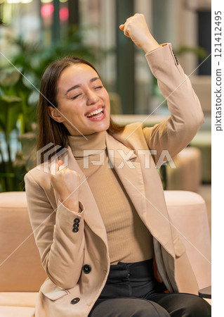 Excited successful businesswoman in formals celebrating success victory good news in office lobby Excited successful businesswoman in formals celebrating success victory good news in office lobby 121412495