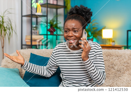 African American woman angry phone call sofa gestures upset expression frustration indoors African American woman angry phone call sofa gestures upset expression frustration indoors 121412530