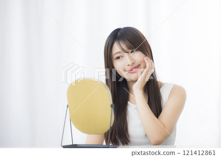A young woman looks in the mirror and worries about her skin A young woman looks in the mirror and worries about her skin 121412861