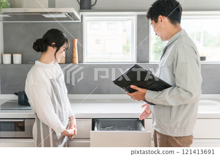 一位女家庭主婦從廚房的水管工和設備店收到有關洗碗機和洗碗機的說明。 一位女家庭主婦從廚房的水管工和設備店收到有關洗碗機和洗碗機的說明。 121413691