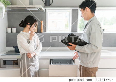 一位女家庭主婦從廚房的水管工和設備店收到有關洗碗機和洗碗機的說明。 121413692