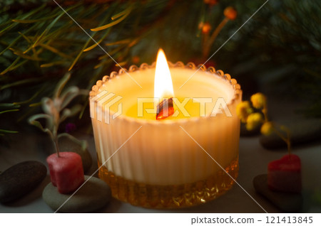 a beautiful scented candle in a transparent holder burns on a dark background. High quality photo 121413845