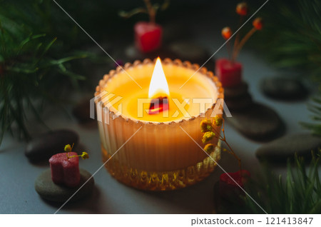 a beautiful scented candle in a transparent holder burns on a dark background. High quality photo 121413847