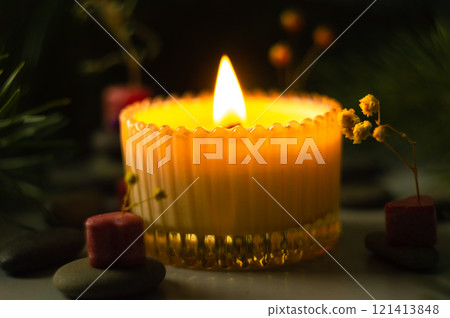 a beautiful scented candle in a transparent holder burns on a dark background. High quality photo 121413848