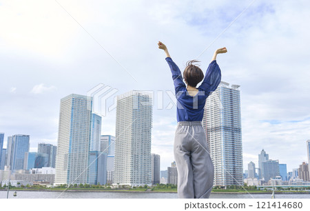 Woman taking a deep breath outside, back view 121414680