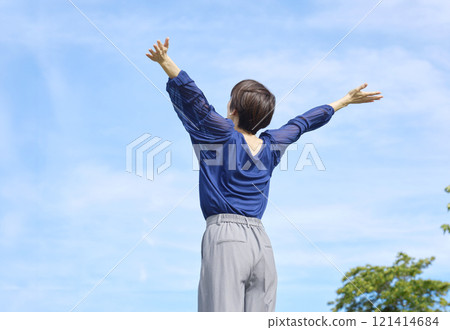 Woman taking a deep breath outside, back view 121414684