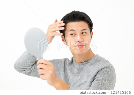 A man who cares about his hair while looking in the mirror A man who cares about his hair while looking in the mirror 121415166