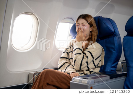 A tired, sleepy Asian woman yawning, feeling sleepy during the long flight to somewhere. A tired, sleepy Asian woman yawning, feeling sleepy during the long flight to somewhere. 121415260