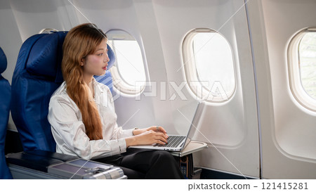 An Asian businesswoman gazes out the window while working on her laptop during the flight. An Asian businesswoman gazes out the window while working on her laptop during the flight. 121415281