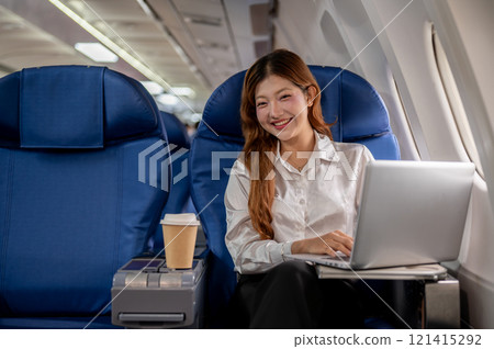 A confident, attractive Asian businesswoman sits on the plane, flying abroad for a business meeting. 121415292