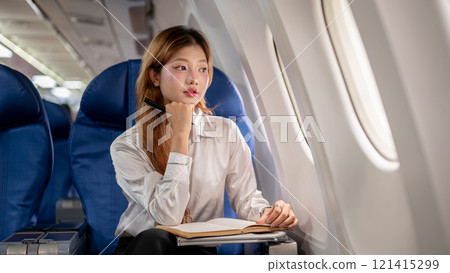 A businesswoman flying abroad for a business meeting gazes out the window during the flight. 121415299