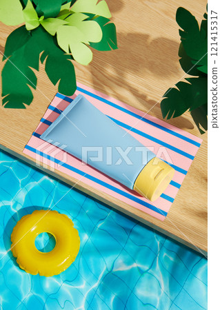 Sunscreen ads use the concept of a miniature pool. A blue tube replica was set on a pink paper mat with a palm tree on a wooden platform, while an inflatable ring floated on the water. High angle. 121415317