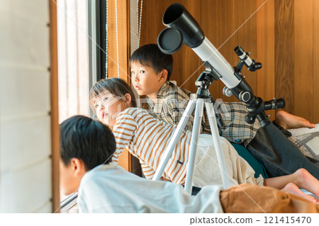 Children, brothers, and sisters playing with a telescope during summer vacation (cottage, villa, mountain hut, camping, glamping) 121415470